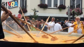  Cooks and volunteers stir eggs on an oversize pan at a Giant Omelet event in Malmedy, Belgium, August 2017.