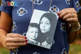 Leigh Boughton Small, an adoptee from Vietnam, poses with a photo of her and her mother as a child and her birth mother, at her home in the US state of Maine on October 29, 2019.