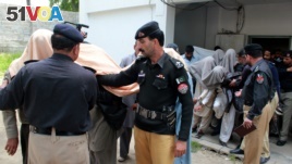 Pakistani police officers escort members of a local tribal council, with their faces covered outside a court in Abbottabad, Pakistan, May 5, 2016. 