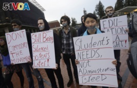 In this photo from 2014, students hold signs as they protest a series of tuition increases planned for the University of California