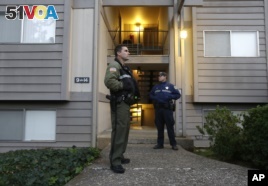 Douglas County Deputy Sheriff Greg Kennerly, left, and Oregon State Trooper Tom Willis, stand guard outside the apartment building, Oct. 2 2015, where alleged Umpqua Community College gunman Chris Harper Mercer lived, in Roseburg, Ore. (AP Photo/Rich Pedroncelli)