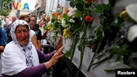 A woman cries beside a truck carrying 136 coffins of newly identified victims of the 1995 Srebrenica massacre, in front of the presidential building in Sarajevo July 9, 2015. The bodies will be on July 11, the anniversary of the massacre. (REUTERS/Dado Ruvic)