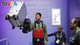 Eric Lynn lifts a 50 pound suitcase with the help of a powered arm similar to the Sarcos Robotics Guardian XO at the Delta Airlines booth during the CES tech show, Wednesday, Jan. 8, 2020, in Las Vegas.