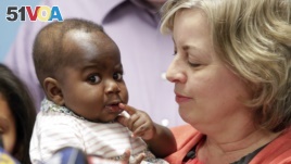 Foster mom Nancy Swabb holds Dominique, a 10-month-old baby born with two spines and an extra set of legs protruding from her neck during a news conference, March 21, 2017, at Advocate Children's Hospital in Park Ridge, Ill. (AP Photo/Teresa Crawford)