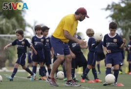 In this 2014 photo, Lee Santamaria, front, teaches children during a soccer camp held in Miami, Florida.
