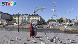 Tourists feed sea gulls in front of the Presidential palace in Helsinki, Finland, Thursday, June 28, 2018. (Onni Ojala/Lehtikuva via AP)