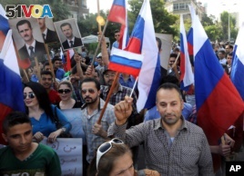 This photo from the Syrian official news agency SANA shows Syrians rallying in front of the Russian Embassy in Damascus to show their thanks to Russia for its intervention in Syria, Oct. 13, 2015. But few Syrians who leave their country are finding Russia welcoming. 