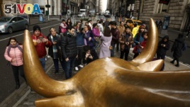 Tourists gather to photograph the Wall Street Bull in the New York Financial District, Jan. 12, 2017.