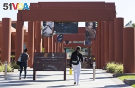 FILE - Students walk past the Harriet and Charles Luckman Fine Arts Complex at the The Cal State University, Los Angeles campus Thursday, April 25, 2019. (AP Photo/Damian Dovarganes)
