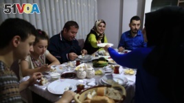 On the first day of the Muslim holy month of Ramadan, Selami Aykut, 38, center, and his family observe the sahoor traditional breakfast of Ramadan, in Istanbul, after being woken by street drummers early Monday, June 6, 2016.