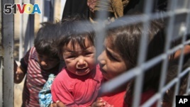 A Syrian child carries a baby crying while they wait with others to cross back to the border town of Tal Abyad in Syria from Turkey, at the border crossing in Akcakale, southeastern Turkey, June 17, 2015. 