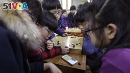 Children watch a smartphone screen showing the live broadcast of the Google DeepMind Challenge Match between Google's artificial intelligence program, AlphaGo, and South Korean professional Go player Lee Sedol, at Lee's Baduk Center in Seoul, South Korea.