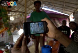 Rohingya Muslim refugee Mohammad Karim, 26, shows a mobile video of Gu Dar Pyin's massacre inside his kiosk in Kutupalong refugee camp, Bangladesh, Jan. 14, 2018.