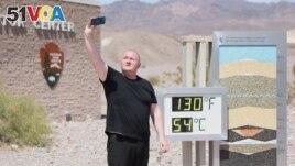 Scott Hughes, of Swansea, Wales, UK, takes a selfie next to a digital display of an unofficial heat reading at Furnace Creek Visitor Center during a heat wave in Death Valley National Park in Death Valley, California, on July 16, 2023. (Photo by Ronda Churchill / AFP)