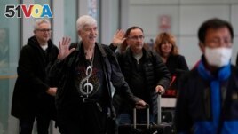 Philadelphia Orchestra's 73-year-old violinist Davyd Booth, second left, waves as he walks ahead of our members upon arriving at the Beijing Capital International Airport on Tuesday, Nov. 7, 2023. (AP Photo/Ng Han Guan)