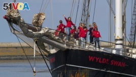 Dutch teens cheer on their schooner Wylde Swan after sailing home from the Caribbean across the Atlantic Ocean when coronavirus lockdowns prevented them from flying, in the port of Harlingen, northern Netherlands, Sunday, April 26, 2020. (AP Photo/Peter Dejong)