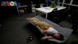 FILE - A worker sleeps in the office after finishing work early morning, in Beijing, China, April 27, 2016. (REUTERS/Jason Lee)