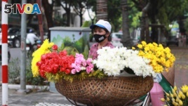 A flower vendor wearing a face mask to protect against the coronavirus waits for customers in Hanoi, Vietnam, Monday, Aug. 3, 2020. Vietnam has tightened travel and social restrictions after the country's death toll of COVID-19 to six. (AP Photo/Hau)