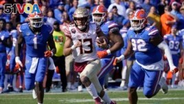 The Florida State quarterback is chased by players from Florida in the last game of the regular season for each team. Neither team won more games than it lost last year. (AP Photo/John Raoux)