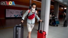 A Russian tourist carries his luggage upon his arrival at Bali's international airport, Indonesia on Friday, Feb. 4, 2022. (AP Photo/Firdia Lisnawati)