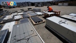 FILE - Dwight Clark inspects a used solar panel at We Recycle Solar on Tuesday, June 6, 2023, in Yuma, Ariz. (AP Photo/Gregory Bull)