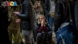 A woman reacts as she waits for a train trying to leave Kyiv, Feb. 24, 2022, as Russia launched its invasion of Ukraine. (AP Photo/Emilio Morenatti)