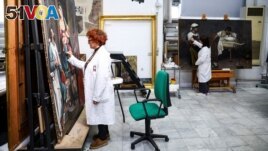 Restorers Alessandra Zarelli and Rossana Giardina work on paintings at the painting and wood materials restoration laboratory inside the Vatican Museums, at the Vatican, December 11, 2023. (REUTERS/Guglielmo Mangiapane)