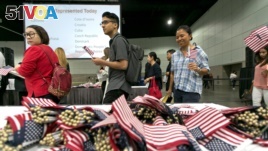FILE - Immigrants pick flags as they arrive to take their citizenship oath during naturalization ceremonies at a U.S. Citizenship and Immigration Services (USCIS) ceremony in Los Angeles, Sept. 20, 2017.