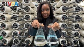 Lakeisha Bryant, public information representative at the Santa Clara Valley Water District, holds flasks of water before and after it is purified at the Silicon Valley Advance Purification Center on December 13, 2023, in San Jose, California. (AP Photo/Terry Chea)