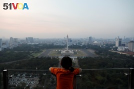 A girl looks on National Monument (Monas) as smog covers the capital city of Jakarta, Indonesia, July 4, 2019. REUTERS/Willy Kurniawan