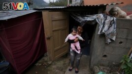 Single mother Katherine Gualotuna holds her four-month-old daughter Arleth outside a one-bedroom shack where they live with Gualotuna's parents in Z<I>&#</I>225;mbiza, a rural town northeast of Quito, Ecuador on November 15, 2022. (AP Photo/Dolores Ochoa)