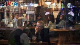 FILE - People sit in a bar in Stockholm, Sweden, on March 25, 2020. Sweden wants to cut red tape when it comes to dancing. (AP Photo/David Keyton, File)