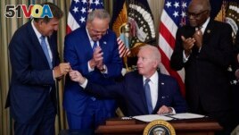 President Joe Biden hands the pen he used to sign the climate change and health care bill to Sen. Joe Manchin, D-W.Va., in the State Dining Room of the White House in Washington, Tuesday, Aug. 16, 2022. (AP Photo/Susan Walsh)