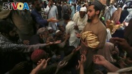 A worker distributes free traditional roti or bread among needy people at a restaurant, in Peshawar, Pakistan on April 16, 2023. (AP Photo/Muhammad Sajjad)