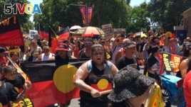 FILE - People carry Australian Aboriginal flags during a demonstration on Australia Day in Sydney, Jan. 26, 2019. 