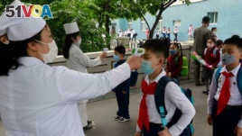 FILE - Kim Song Ju Primary School students have their temperatures checked in Pyongyang, North Korea, June 3, 2020. 