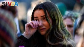 FILE - A mourner wipes a tear during a vigil honoring the students killed and injured in Monday's shootings at Michigan State University, at The Rock on the grounds of the university in East Lansing, Mich., Wednesday, Feb. 15, 2023. (AP Photo/Paul Sancya)