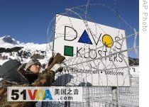 Members of the Swiss Army place barbed wire on a fence to secure the area at the helicopter landing place for the World Economic Forum
