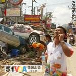 A man talks on his phone near smashed cars along Patong Beach in Thailand