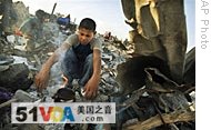 A Palestinian youth boils tea on a fire in the rubble of his family home in Jebaliya, northern Gaza, 22 Jan 2009