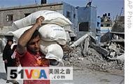 A Palestinian carries sacks of flour at the UNRWA warehouse in Jebaliya refugee camp in Gaza City, 26 Jan 2009