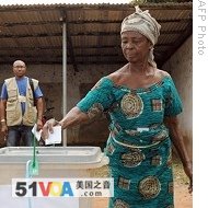 ECOWAS observer watches woman casting her vote in Nkawas, in Tain constituency, 02 Jan 2009