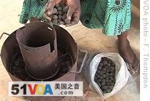 Fatou Camara, 45, cooks with green charcoal in an improved stove 