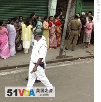 Voters waiting to cast their votes, as security personnel patrol outside a polling booth in Calcutta, 13 May 2009