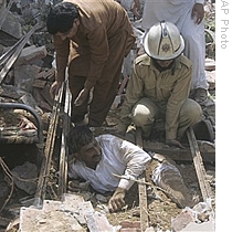 Pakistani rescue worker struggle to recover an injured victim from the rubble at the site of suicide car bombing in Lahore, Pakistan, 27 May 2009