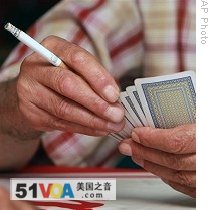 Turkish man smokes a cigarette as he plays cards with friends at a teahouse in Ankara, Turkey, 19 Jul 2009