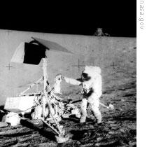 Apollo 12 astronaut Pete Conrad inspects Surveyor 3. The lunar module, Intrepid, can be seen in the distance