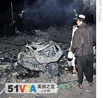 People look at the destruction left by a car bomb in Kandahar, 25 Aug  2009