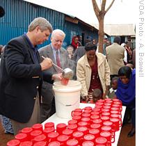 U.S. Secretary of Agriculture Tom Vilsack  (l) and Ambassador Mark Ranneberger feeding school kids in Kibera, Kenya
