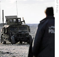An Afghan officer walks towards a US armored vehicle damaged after a suicide attack in Ningarhar province, east of Kabul (File)